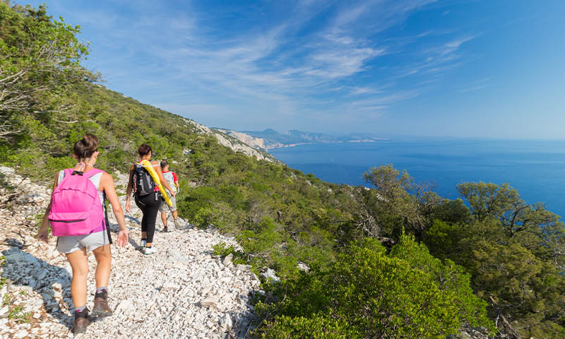 Hikers traversing a coastal path in Sardinia